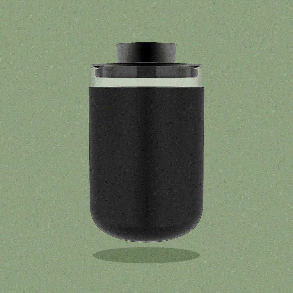 Glass storage jar with black silicone sleeve on green background.